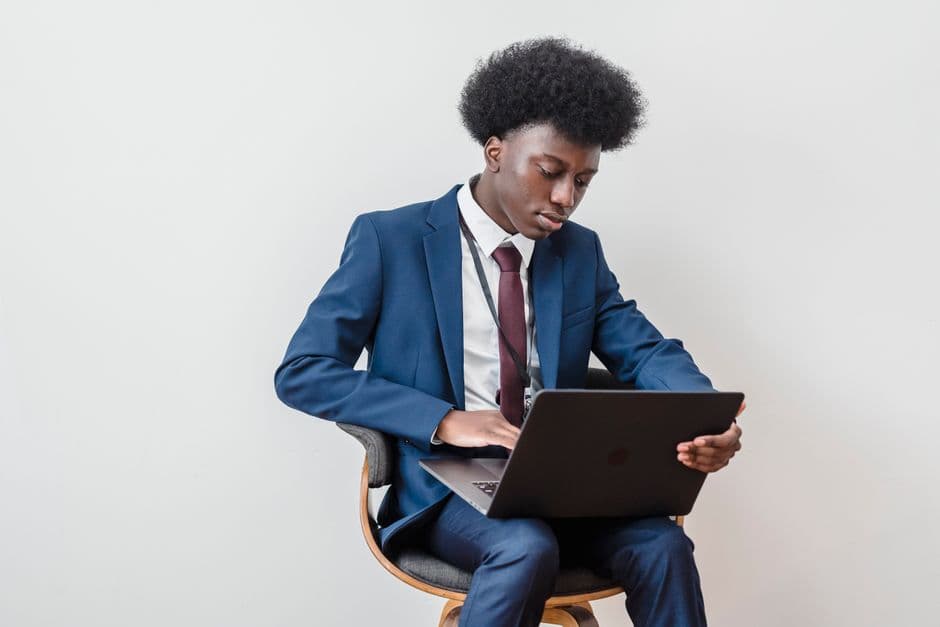 Businessman in a blue suit working on a laptop in a modern office setting.