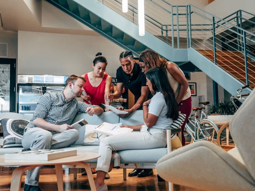 A diverse group of coworkers engaged in brainstorming and planning in a modern office lobby.