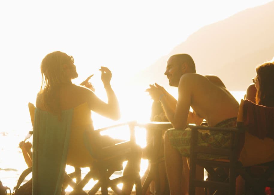 People enjoying a vibrant sunset beach gathering in Naxos, Greece, creating a warm and lively atmosphere.
