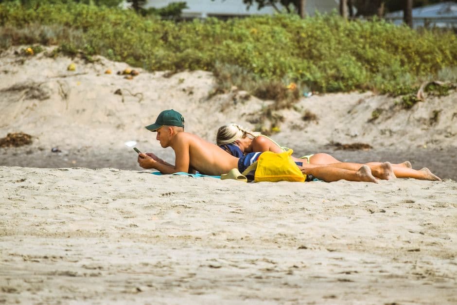 A couple sunbathing and reading on Vagator Beach in Goa, India, enjoying a sunny day.