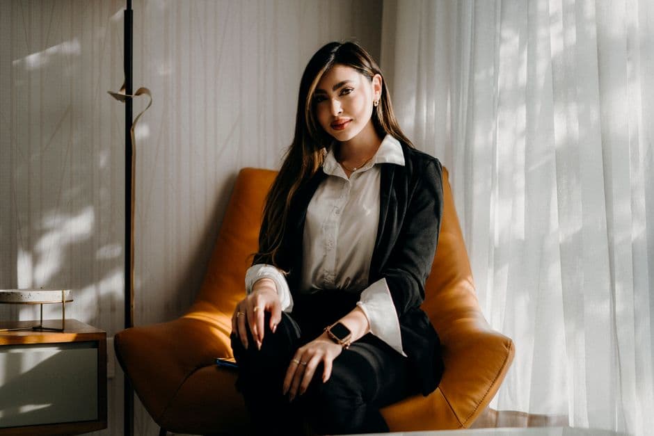 Confident woman sitting in modern office chair with natural lighting.